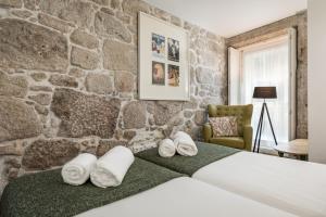 a bedroom with a stone wall and a bed with towels at Rua de Trás Apartments in Porto