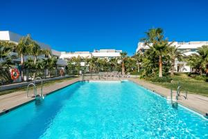 a swimming pool with blue water and palm trees at Oasis by the Sea in La Cala de Mijas (La Valvega) in Mijas Costa