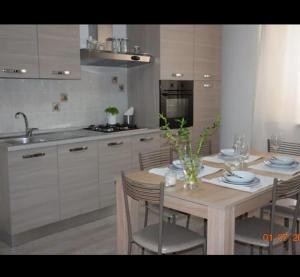a kitchen with a wooden table with chairs and a sink at EMMANUEL CASA VACANZE in Pozzallo