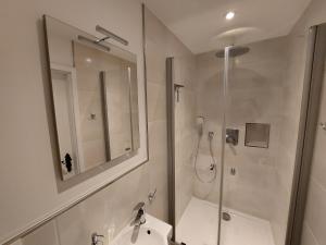 La salle de bains est pourvue d'une douche, d'un lavabo et d'un miroir. dans l'établissement Ferienwohnung Koblenz Goldgrube, à Coblence