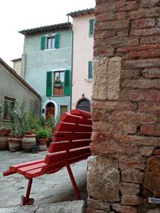 a red bench sitting next to a stone wall at Casa di Laura in Chianciano Terme