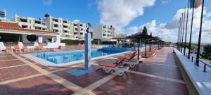 a swimming pool with lounge chairs and a hotel at Albufeira Jardim by Umbral in Albufeira