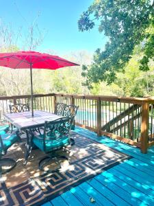 a picnic table with a red umbrella on a deck at Getaway Oasis w/Huge Deck + pool/spa - lake conroe in Willis