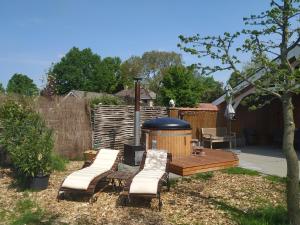 een achtertuin met een houten terras met stoelen en een prieel bij Chalet "Het Biggetje" met hottub in Volkel