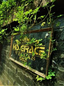 a sign on the side of a brick wall with plants at His grace villas in Kottakkal