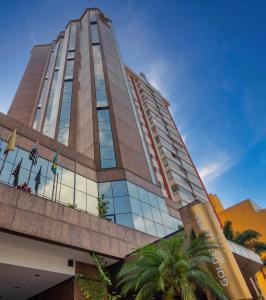 a tall building with palm trees in front of it at Golden Tower Pinheiros by Fênix Hotéis in Sao Paulo