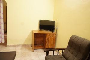 a tv sitting on top of a wooden stand next to a chair at BREEZ VILLA in Madikeri