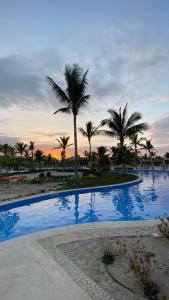 Una piscina con palmeras y una puesta de sol. en WASAN LUXURY RESIDENCE HAWANA Salalah, en Salalah