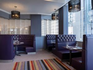 Leonardo Hotel Leeds في ليدز: غرفة طعام مع الأرائك والطاولات والنوافذ