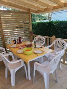 a wooden table and chairs on a wooden deck at mobil home tout confort 6 personnes climatisé au pied du Luberon in La Roque-dʼAnthéron