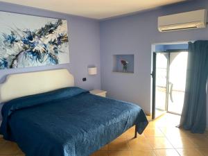 a blue bedroom with a bed with a blue blanket at Luna Convento Copanello B&B in Stalettì
