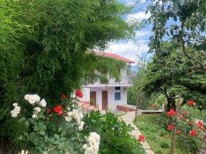 a house with a garden with red and white flowers at Ramneek Homestay in Joshīmath