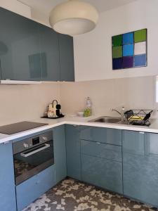 a kitchen with blue cabinets and a sink at La maison de toujours in La Garenne-Colombes