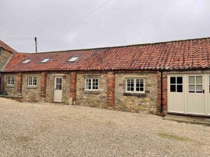 a row of brick buildings with white doors and windows at Beck House Cottages in Pickering