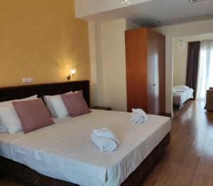 a bedroom with a large bed with towels on it at Grand Olympic Hotel Loutraki in Loutraki