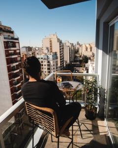 une femme assise sur une chaise sur un balcon dans l'établissement Isi Baires Alquiler Temporario, à Buenos Aires
