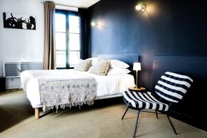 a bedroom with a large bed and a chair at Hôtel Le Collonges in Brive-la-Gaillarde