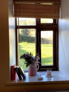 a window with a vase of flowers on a table at Y Felin Bed and Breakfast and Smallholding in Caersws