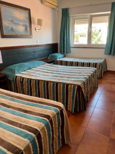 a hotel room with three beds with striped sheets at O Cantinho in Benavente