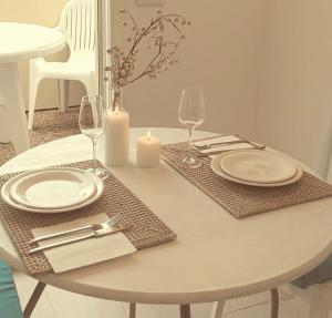einen weißen Tisch mit Tellern, Gläsern und einer Kerze in der Unterkunft Attico Victoria Palace suggestivo e spettacolare in Menton
