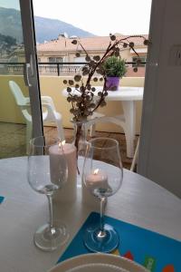 zwei Weingläser auf einem Tisch mit einer Kerze in der Unterkunft Attico Victoria Palace suggestivo e spettacolare in Menton