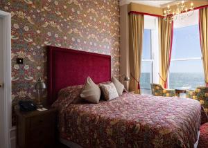 a bedroom with a large bed with a red head board at Langham Hotel Eastbourne in Eastbourne