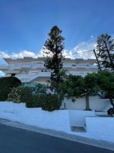un bâtiment blanc avec des arbres devant lui dans l'établissement Aeolos Apartments Kolymbari, à Kolymbari