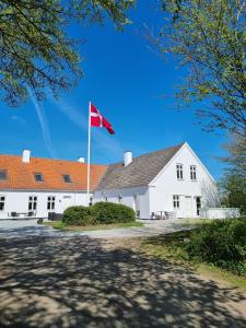 un bâtiment blanc avec un drapeau rouge devant lui dans l'établissement Marielyst Sleep´n Go, à Væggerløse