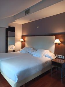 ein großes weißes Bett in einem Zimmer mit einem Tisch in der Unterkunft ARVA Spa París in León + 148 Fotos