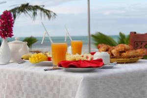 a table with a plate of food and orange juice at Serenity Luxury Villas in Paje