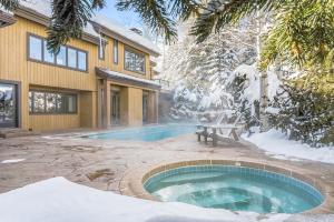 a swimming pool in front of a house in the snow at Trails Edge by Snowmass Vacations in Aspen