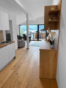 una cucina e un soggiorno con armadi bianchi e pavimenti in legno di Traum Panorama Apartment mit Berg & Seeblick ad Altmünster