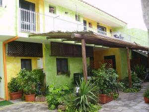 una casa verde e gialla con balcone e piante di B&B Rita E Renzo a Riola Sardo
