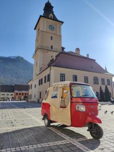 a small car parked in front of a building with a clock tower at Colfly Studios in Braşov