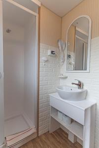 La salle de bains blanche est pourvue d'un lavabo et d'une douche. dans l'établissement Villa Ghetta Country House, à Leverano