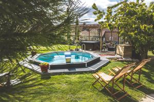 a swimming pool in a yard with two lawn chairs at Au Domaine Fresnois in Fresnes-lès-Montauban