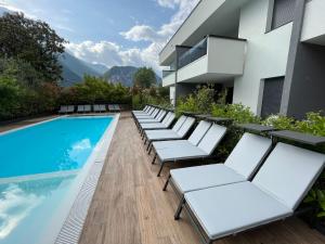 - une rangée de chaises longues blanches à côté de la piscine dans l'établissement Riva Lake Lodge, à Riva del Garda