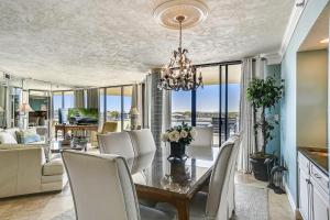 a dining room with a table with white chairs and a chandelier at East Pass Towers 304 Condo in Destin