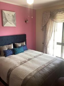 a bedroom with a large bed and a pink wall at Arouca à Varanda in Arouca