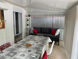 een woonkamer met een tafel en een bank bij Bel Appartement avec Jardin pour 4 Personnes Climatisé avec Accès plage de la Gorguette à pied in Sanary-sur-Mer