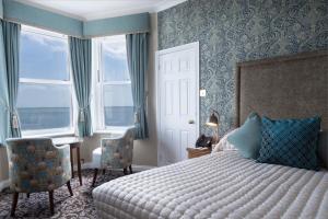 a bedroom with a bed and a chair and a window at Langham Hotel Eastbourne in Eastbourne