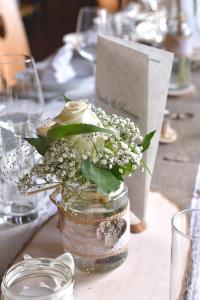 Ein Mason-Glas mit Blumen auf dem Tisch. in der Unterkunft Gasthof Hirschenwirt in Schöder