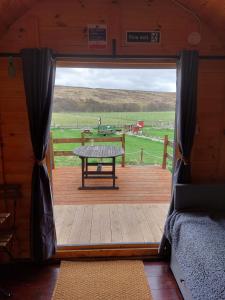 - une vue sur une terrasse couverte en bois avec une table de pique-nique dans l'établissement Pod 4, à Skail