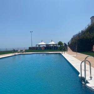 una piscina con acqua blu e un gazebo di Precioso apartamento con piscina a San Luis de Sabinillas