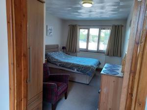 1 dormitorio pequeño con 1 cama y 1 silla en Dunroaming Cottage, en Pendine