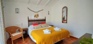 um quarto com uma cama com lençóis amarelos e uma cadeira em Finca La Meica B&B em Casabermeja