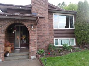 a dog sitting on the porch of a brick house at Main Floor Bright & Spacious Apartment in Lethbridge