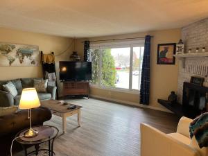 a living room with a couch and a tv at Main Floor Bright & Spacious Apartment in Lethbridge
