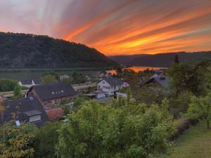 una puesta de sol sobre una ciudad con un río y casas en Traumhaftes Blockhaus am Rhein, en Kamp-Bornhofen