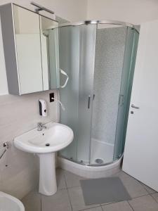 ein weißes Bad mit einer Dusche und einem Waschbecken in der Unterkunft HomeFamily in Lido di Ostia